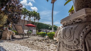 A patio area with a stone bench, a red umbrella, and a decorative stone balustrade. - Angel's Cave (Escazu)