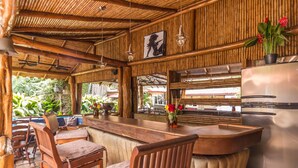A rustic bar area with wooden furniture and a refrigerator. - Angel's Cave (Escazu)