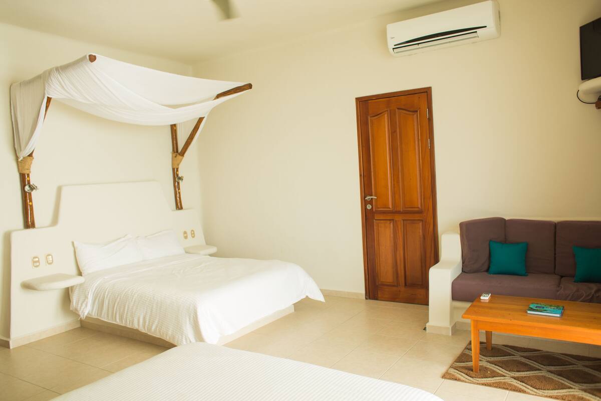 A bedroom with a canopy bed, a sofa, a coffee table, and a door.