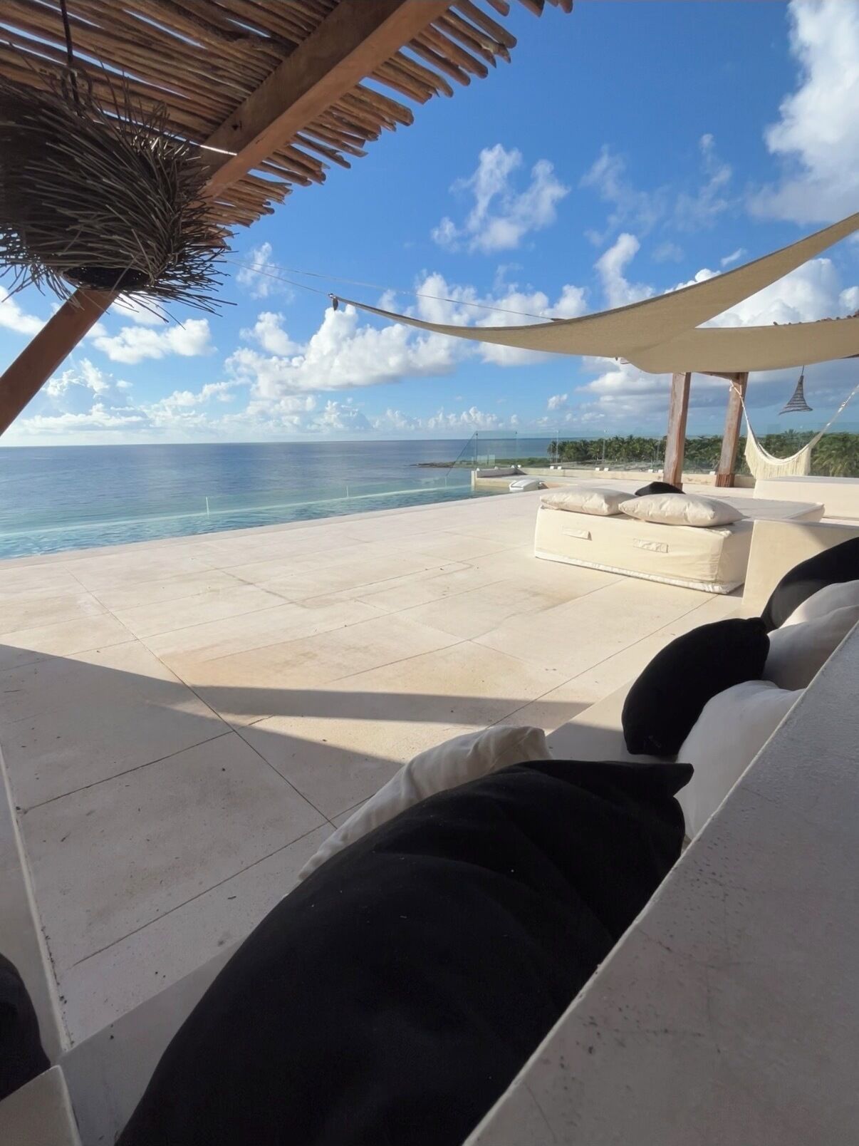 A beachside lounge with a view of the ocean, a hammock, and a pool.