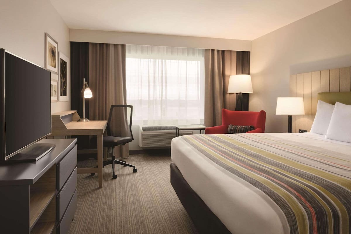 A hotel room with a bed, desk, chair, TV, and two lamps.