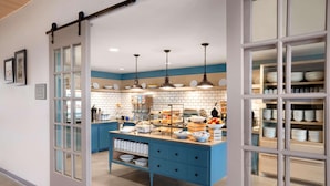 A kitchen with a blue island, white cabinets, and hanging pendant lights. - Country Inn & Suites by Radisson, Ft. Atkinson, WI (Fort Atkinson)