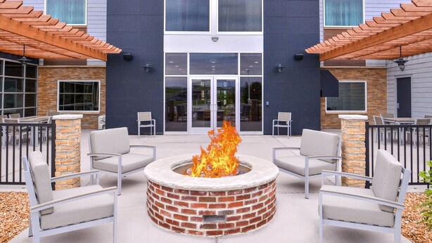 An outdoor seating area with a fire pit, two chairs, and a stone pillar. - Country Inn & Suites by Radisson, Ft. Atkinson, WI (Fort Atkinson)