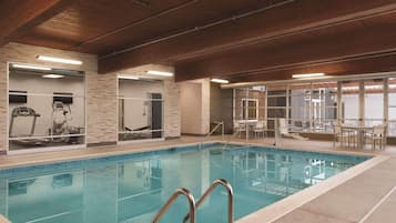 Una piscina interior con equipo de ejercicio, un comedor y vistas al exterior.