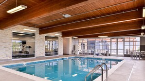 An indoor swimming pool with a clear view of the surrounding area, including a brick wall, a glass door leading to a room, and a seating area with tables and chairs. - Country Inn & Suites by Radisson, Ft. Atkinson, WI (Fort Atkinson)