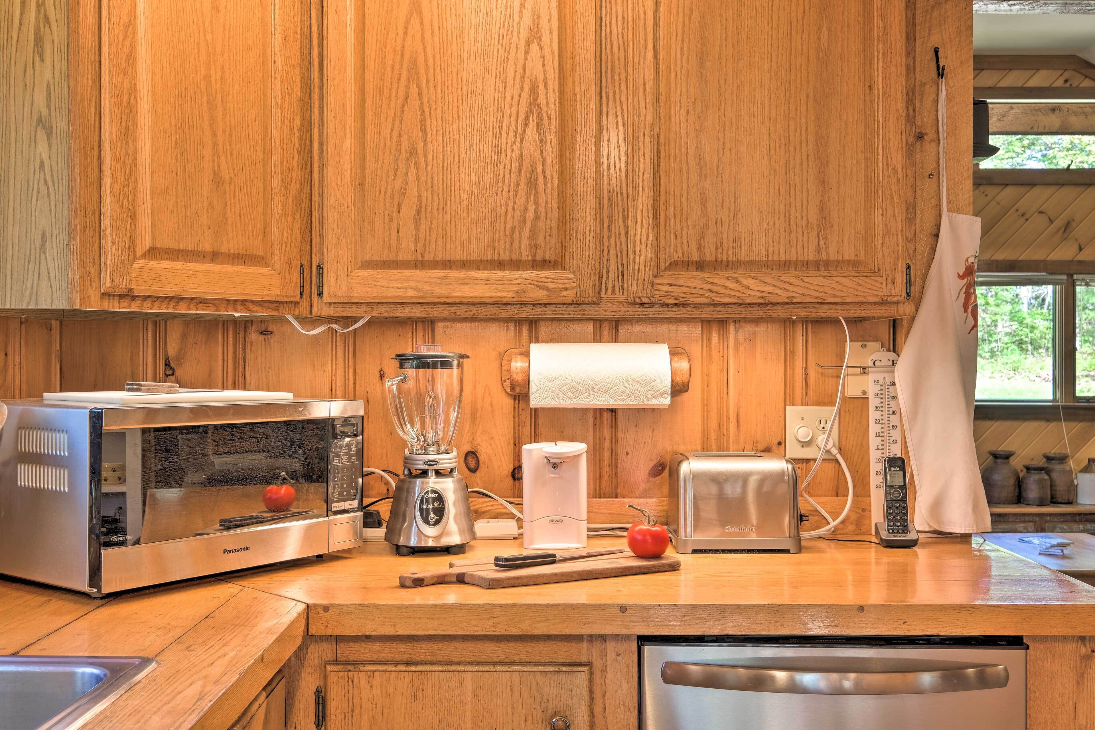 A kitchen with wooden cabinets, a microwave, a toaster, a blender, and a sink.