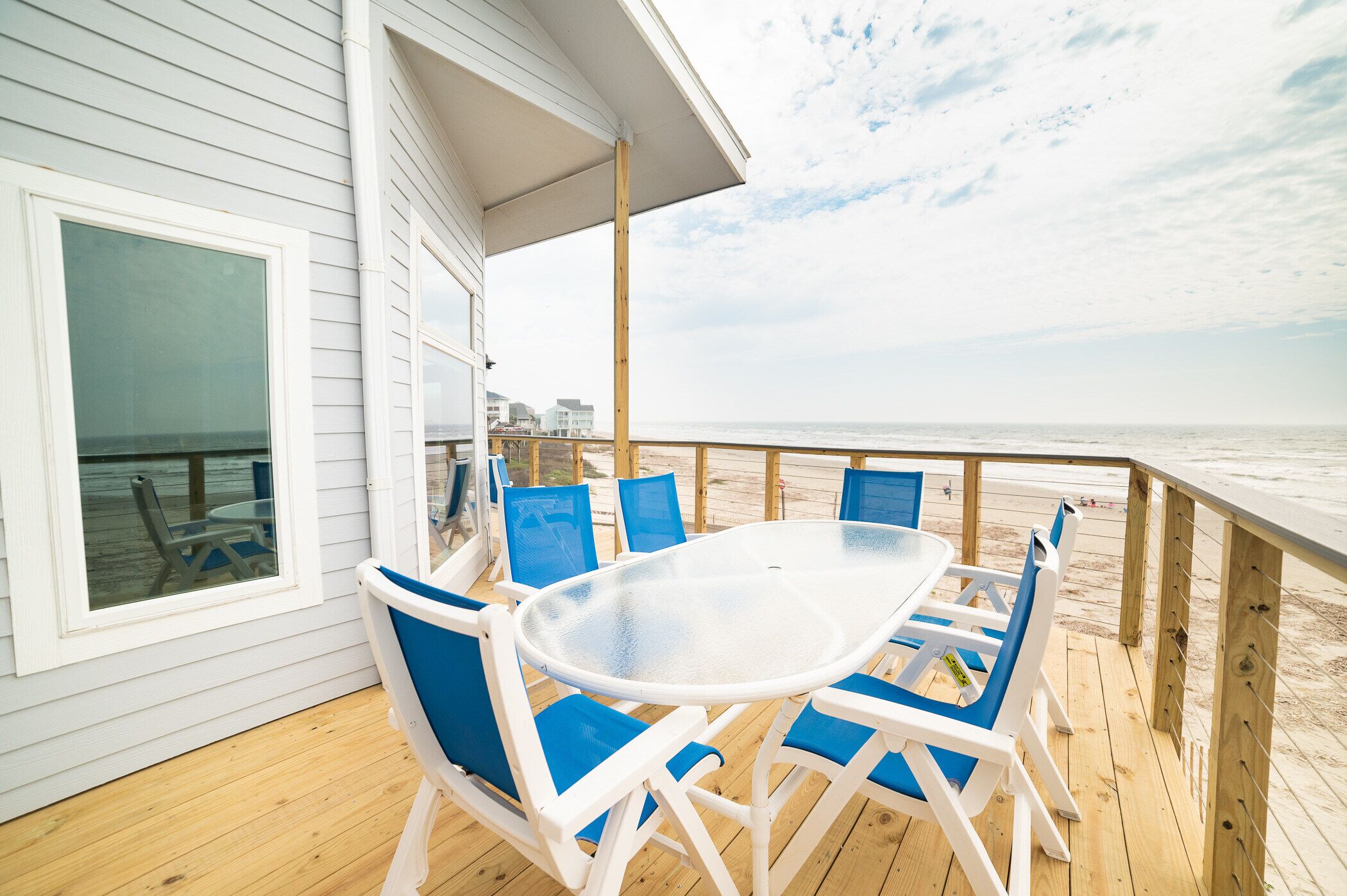 Terraza cubierta al aire libre con una mesa y sillas, con vista a una playa.