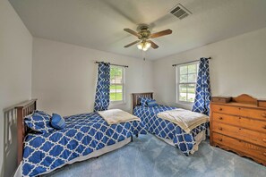Ein Schlafzimmer mit zwei Betten, einem Deckenventilator und einer Holzkommode.