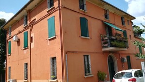 A multi-story building with a flat roof, green shutters, and a balcony with potted plants. - Pisolo home holidays near city center and Sant'Orsola Hospital (Bologna)