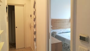 A hotel room with a bed, a thermostat, and a door leading to another room. - Pisolo home holidays near city center and Sant'Orsola Hospital (Bologna)
