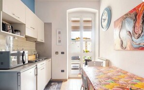 A compact kitchen with a microwave, cabinets, and a dining area with a table and chairs.