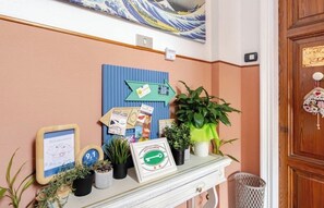 A reception desk with a blue sign, framed pictures, potted plants, and a wooden door with a heart-shaped decoration.