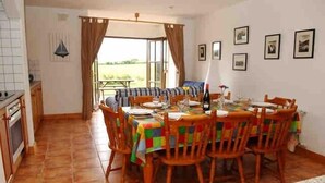 Un coin repas avec une table dressée pour quatre personnes, des chaises en bois et une nappe colorée.
