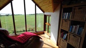 Une pièce dotée d’une grande fenêtre, d’un plafond en bois et d’une bibliothèque.