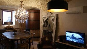A rustic dining area with a wooden table, chairs, a chandelier, and a television. - Mansion - Vallon pont d''arc (Vallon-Pont-D'arc)