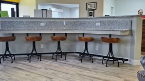 A kitchen with a granite countertop and five wooden stools. - Dawson Inn (Meadow Bridge)