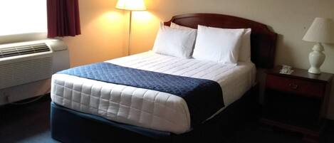 Habitación de hotel con cama, mesita de noche, lámpara, un cuadro en la pared y una ventana con cortinas.