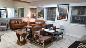 A living room with a sofa, chairs, a coffee table, and a chess table. - Dawson Inn (Meadow Bridge)