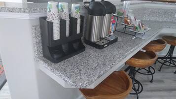 A kitchen counter with a coffee maker, a kettle, and a coffee dispenser.