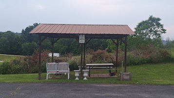 A designated smoking area with a covered bench and picnic table, surrounded by greenery.