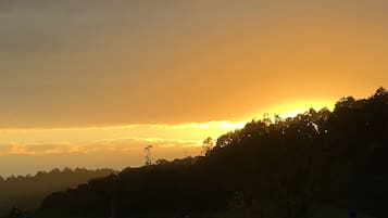 A sunset over a hilly landscape with a road and a bridge in the foreground.