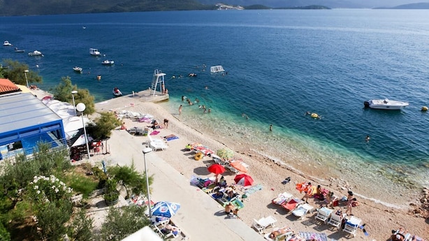 A beach with clear waters, boats, and umbrellas. - Romantic, quite, seafront apartment, sunbeds, barbecue, all by the sea. For 2p (Komarna)