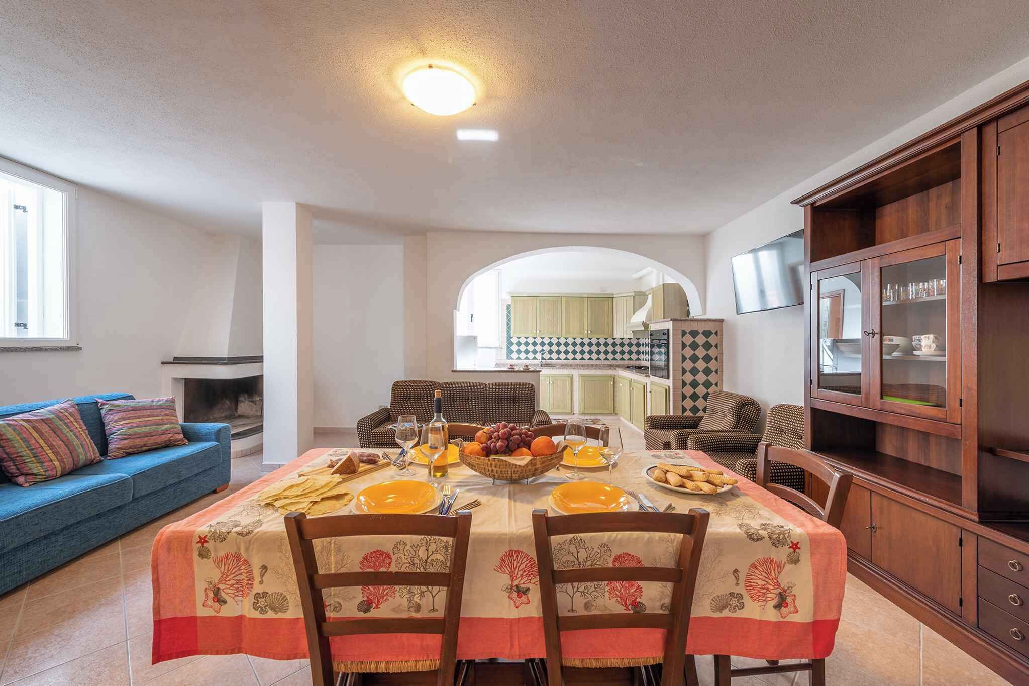 A dining area with a table set for four, a blue sofa, and a kitchen in the background.