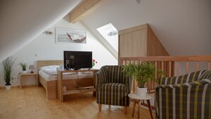 Un acogedor dormitorio estilo loft con una cama, un escritorio con un ordenador, dos sillones a rayas y una mesita con una planta.