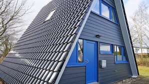 A house with a sloped roof and blue exterior walls.