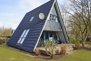 Ein modernes Haus mit geneigtem Dach, großen Fenstern und einer kleinen Terrassenfläche.
