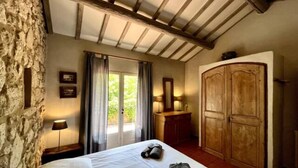 Ein Schlafzimmer mit Bett, Holzschrank, Steinwand und einem Fenster mit Vorhängen.