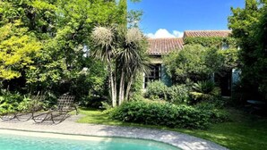 Ein Pool, umgeben von üppiger Vegetation und einem Gebäude mit einem Ziegeldach.
