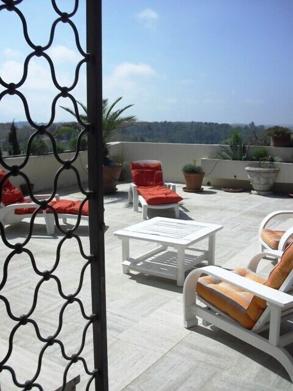 A rooftop terrace with outdoor furniture, potted plants, and a clear view of the surrounding landscape. - Magnifique appartement dominant de 100m2, énorme terrasse vue mer et montagne (Vence)