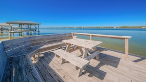Una terrazza in legno con tavoli da picnic e panchine che si affaccia su un lago calmo.