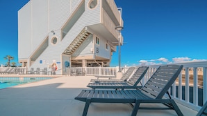 Un hotel fronte mare con piscina, lettini e un design architettonico unico.