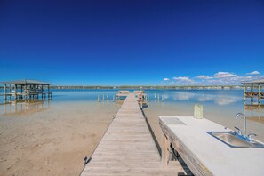 A wooden pier leading to a dock with a sink and benches.