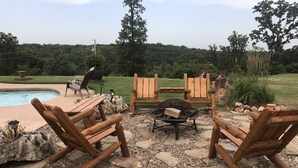 A patio area with wooden Adirondack chairs, a fire pit, and a pool. - HEATED POOL  Grand Serenity is your Oasis on South Grand (Afton)