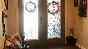 A hallway with a double door featuring decorative glass panels, a bench with cushions, and a wall-mounted plant. - HEATED POOL  Grand Serenity is your Oasis on South Grand (Afton)