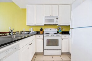 A kitchen with white cabinets, a microwave, a stove, and a refrigerator. - LIGHTHOUSE! Popular Property! ~ 1 BR Beach Front! XTRA BATH! (Gulf Shores)
