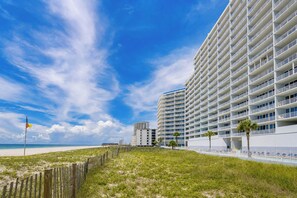 A beachfront hotel with multiple floors, a sandy beach in the foreground, and a clear blue sky. - LIGHTHOUSE! Popular Property! ~ 1 BR Beach Front! XTRA BATH! (Gulf Shores)