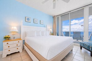 Una habitación de hotel con una cama grande, un balcón con vistas y un ventilador de techo.