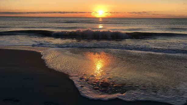 Una playa con olas al atardecer.