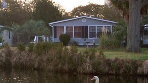Una casa con porche y un cisne en un estanque.