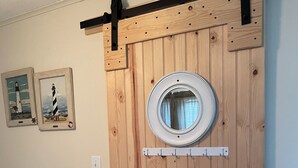 Un armario de madera con un espejo circular, un perchero y dos cuadros en la pared.
