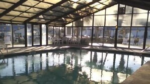 Una piscina interior con paredes de vidrio transparente, que permite vistas al exterior.