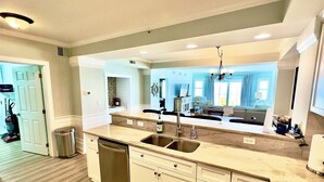 Een moderne keuken met een centraal eiland, roestvrijstalen apparatuur en uitzicht op de woonkamer.