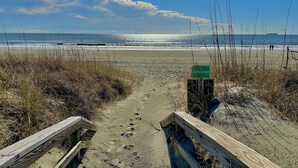 Een strandpad dat naar de oceaan leidt, met een bord waarop 'Dunescape' staat.
