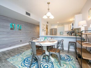 Una cocina moderna con una isla central, armarios blancos y una lámpara colgante.