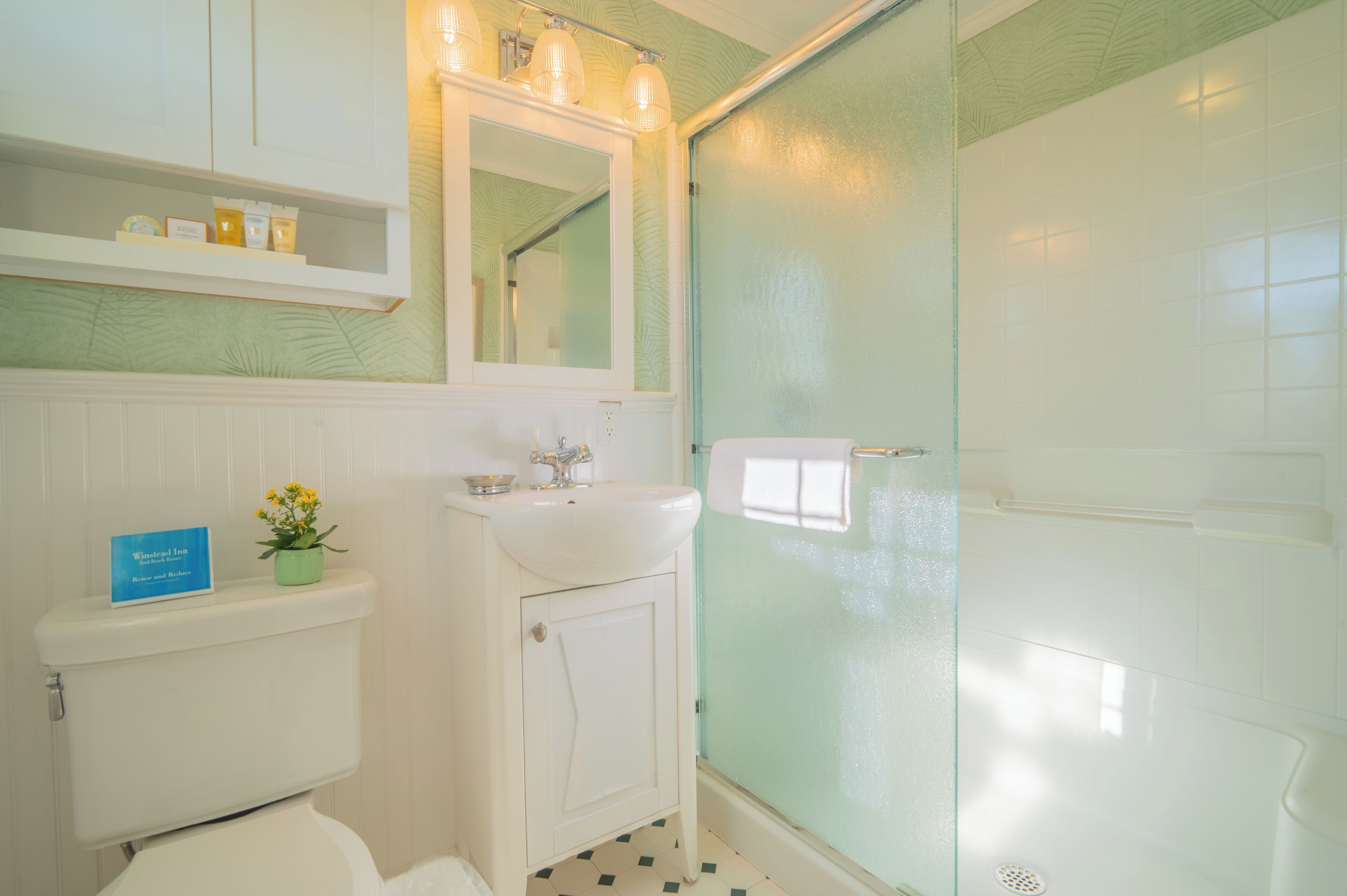 A bathroom with a toilet, sink, and glass shower enclosure.