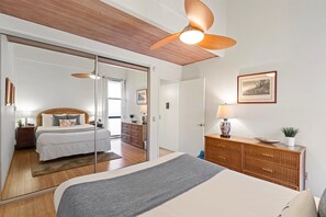 Un dormitorio con una cama, un aparador, un espejo y un ventilador de techo.